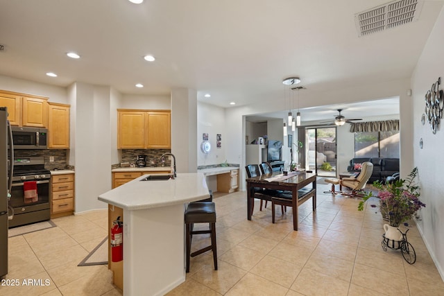 kitchen featuring pendant lighting, appliances with stainless steel finishes, sink, a center island with sink, and a breakfast bar area