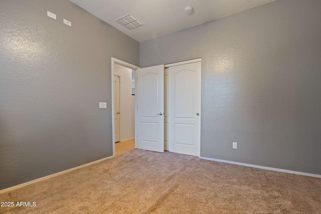 unfurnished bedroom featuring light colored carpet and a closet