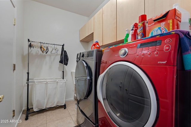 laundry area featuring separate washer and dryer, cabinets, and light tile patterned floors