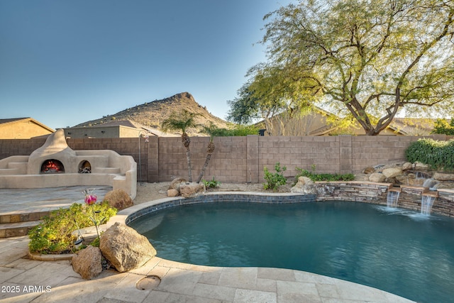 view of swimming pool featuring pool water feature and an outdoor fireplace