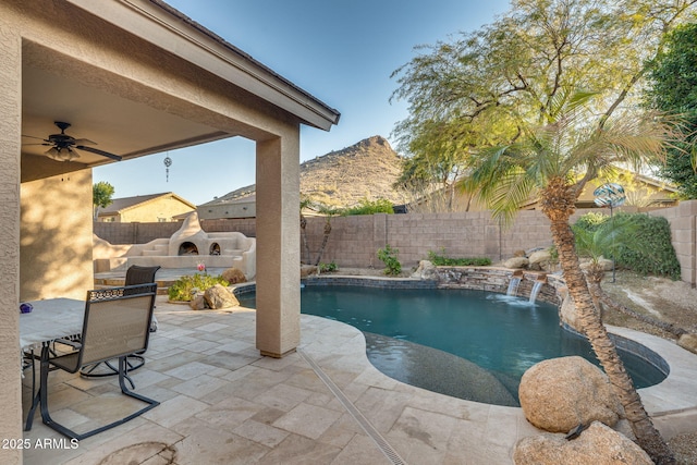 view of pool with exterior fireplace, a patio, pool water feature, a mountain view, and ceiling fan