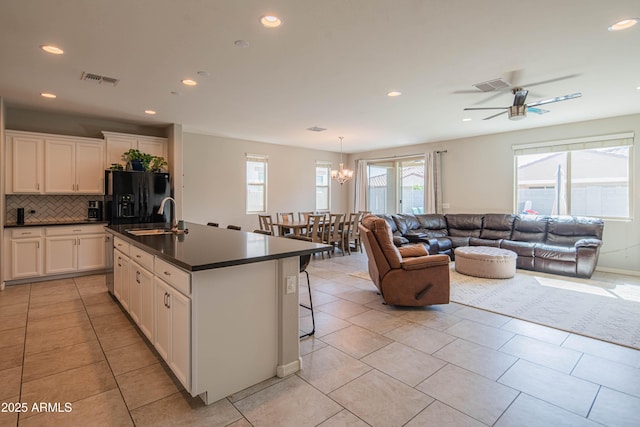 kitchen with tasteful backsplash, dark countertops, black refrigerator with ice dispenser, open floor plan, and a sink