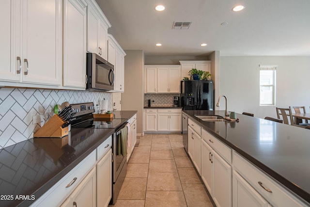 kitchen featuring light tile patterned floors, a sink, visible vents, appliances with stainless steel finishes, and dark countertops