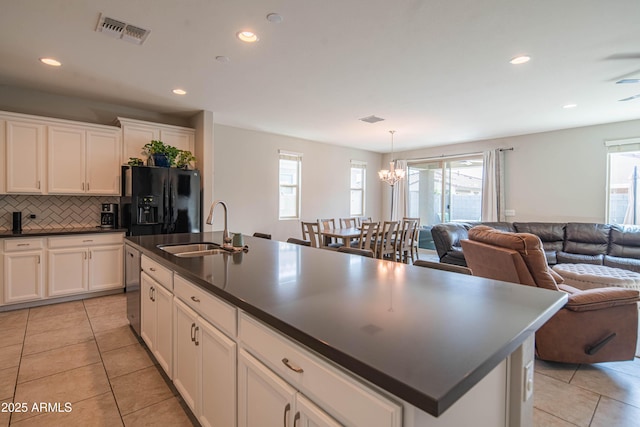 kitchen with a sink, visible vents, open floor plan, black fridge, and dark countertops