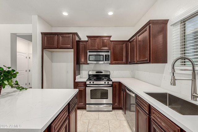 kitchen featuring appliances with stainless steel finishes, recessed lighting, a sink, and light stone countertops