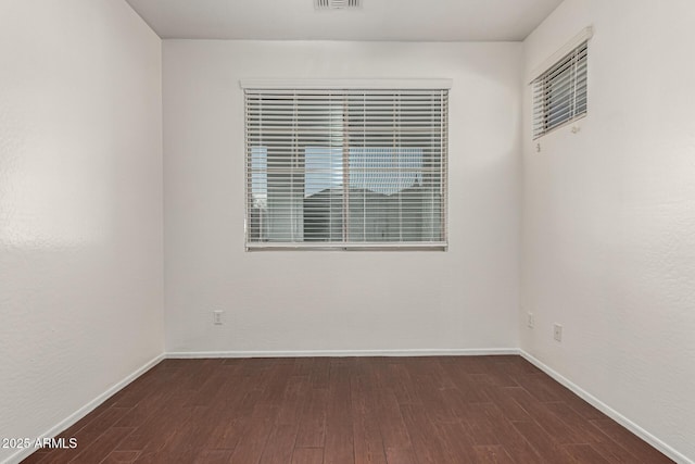 spare room featuring visible vents, baseboards, and dark wood-type flooring