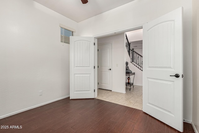 empty room featuring baseboards, stairs, a ceiling fan, and wood finished floors