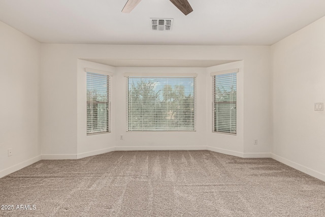 empty room with visible vents, plenty of natural light, carpet flooring, and ceiling fan