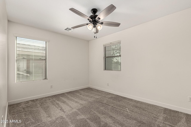 spare room with carpet floors, visible vents, ceiling fan, and baseboards