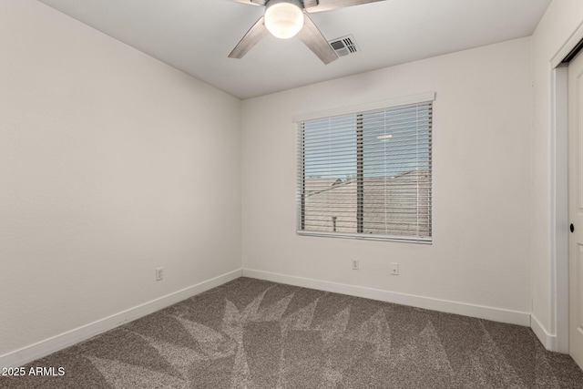 spare room with ceiling fan, visible vents, dark carpet, and baseboards