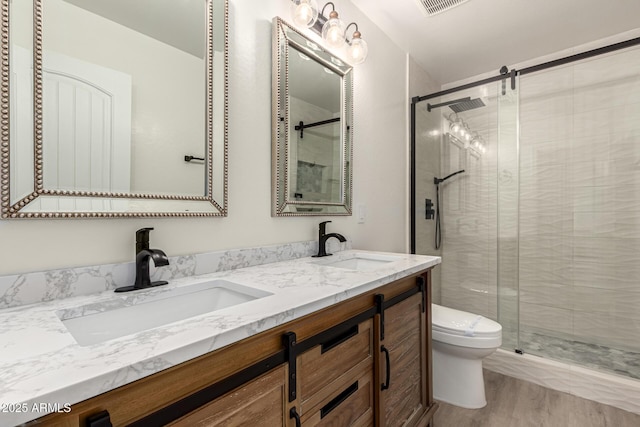 bathroom with a sink, a shower stall, toilet, and double vanity