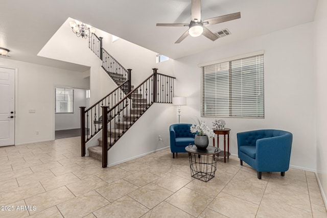 sitting room with stairs, tile patterned floors, visible vents, baseboards, and ceiling fan with notable chandelier