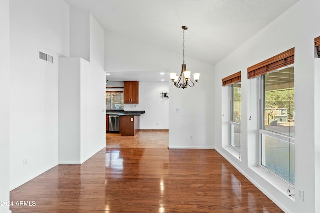 unfurnished dining area with a notable chandelier, wood-type flooring, and lofted ceiling