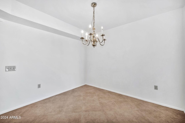 spare room with a chandelier and light tile patterned floors