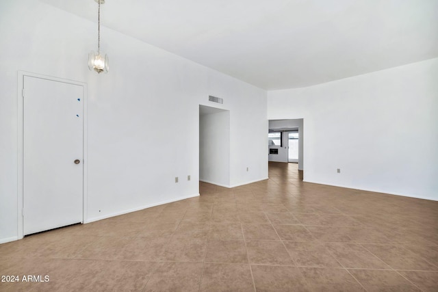 spare room featuring a chandelier, high vaulted ceiling, and light tile patterned floors