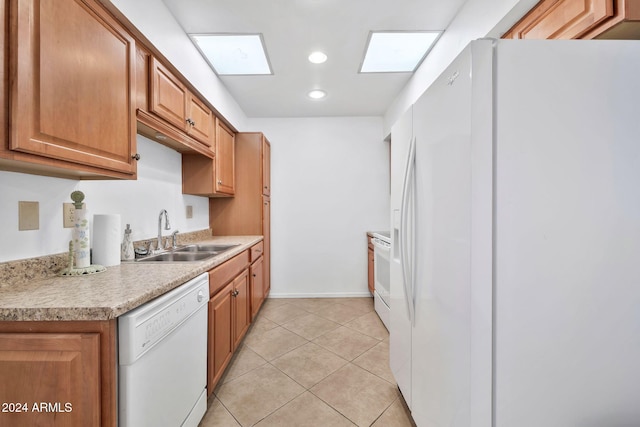 kitchen with sink, a skylight, white appliances, and light tile patterned floors