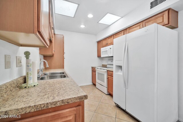 kitchen with sink, a skylight, white appliances, and light tile patterned floors