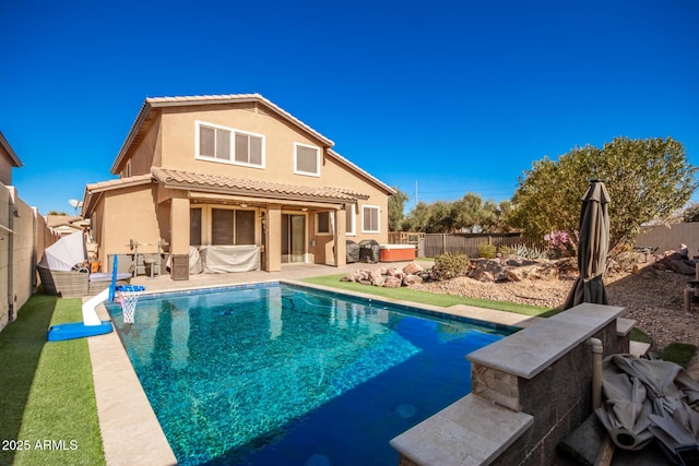 rear view of property with a fenced in pool and a patio