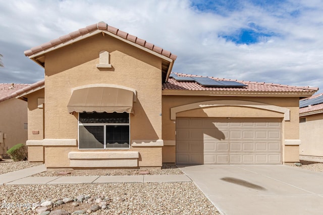 view of front of property featuring roof mounted solar panels, stucco siding, concrete driveway, and a tile roof