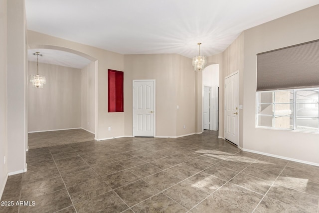 unfurnished room with arched walkways, baseboards, and an inviting chandelier