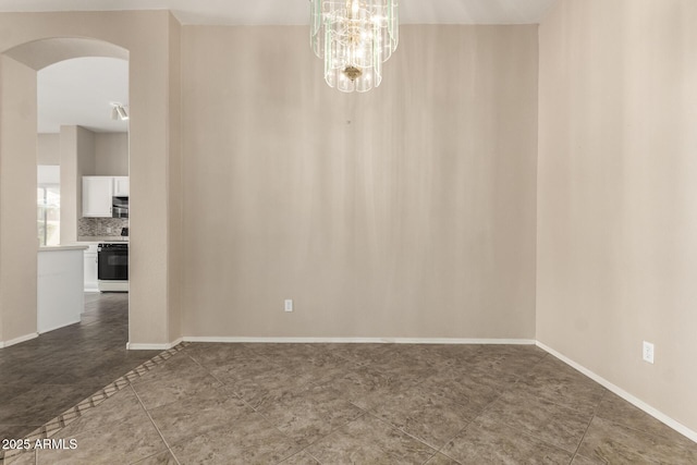 spare room with baseboards, arched walkways, and an inviting chandelier