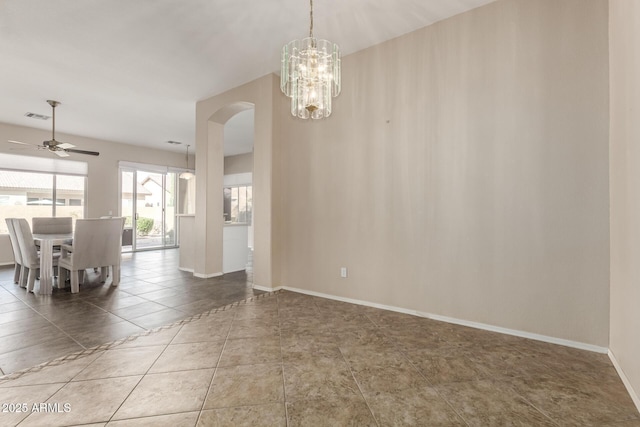 unfurnished dining area featuring tile patterned floors, visible vents, ceiling fan with notable chandelier, arched walkways, and baseboards