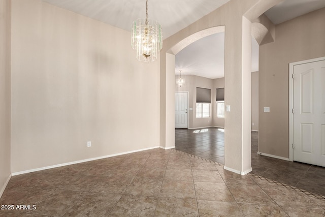 empty room with tile patterned flooring, a notable chandelier, arched walkways, and baseboards