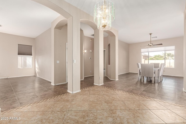 unfurnished dining area featuring tile patterned floors, visible vents, ceiling fan with notable chandelier, arched walkways, and baseboards