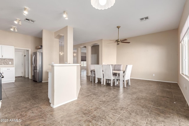 dining space featuring arched walkways, visible vents, baseboards, and ceiling fan