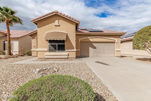 view of front of property with stucco siding, roof mounted solar panels, concrete driveway, a garage, and a tiled roof