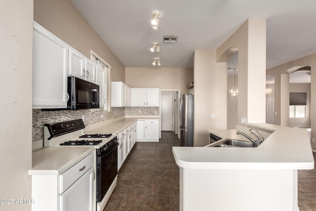 kitchen with a sink, range with gas stovetop, freestanding refrigerator, black microwave, and decorative backsplash