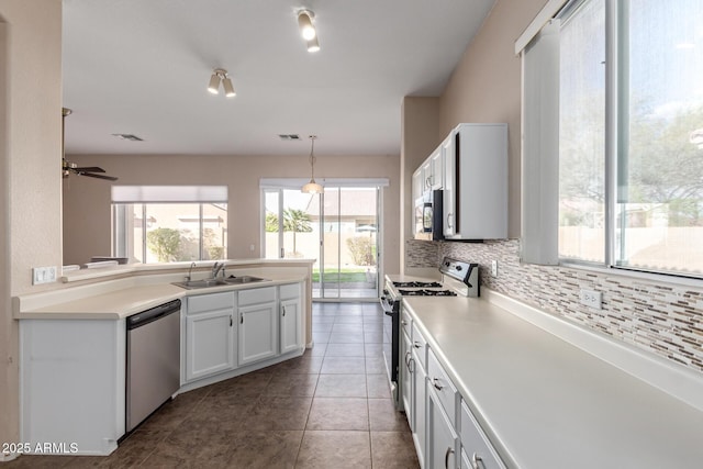 kitchen with a sink, stainless steel appliances, tile patterned floors, decorative light fixtures, and backsplash