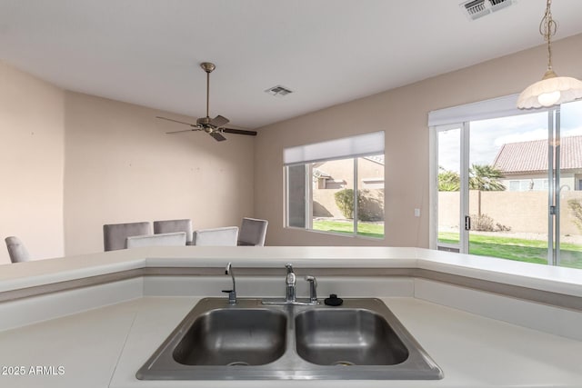 kitchen featuring light countertops, decorative light fixtures, visible vents, and a sink