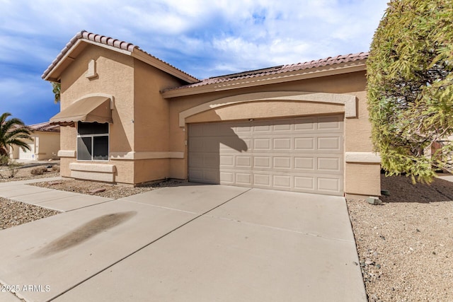 mediterranean / spanish house featuring a tile roof, a garage, driveway, and stucco siding