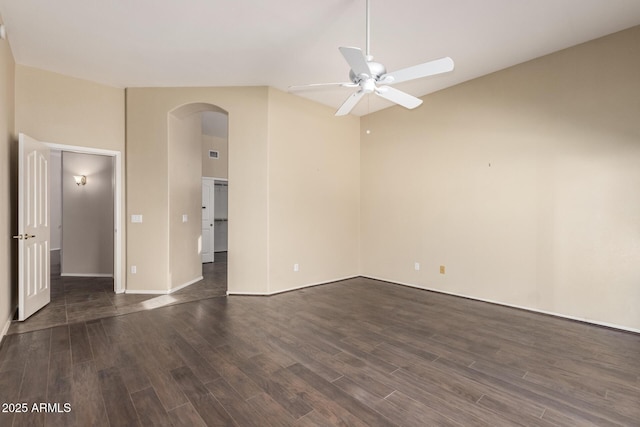 unfurnished room featuring ceiling fan, arched walkways, and dark wood finished floors