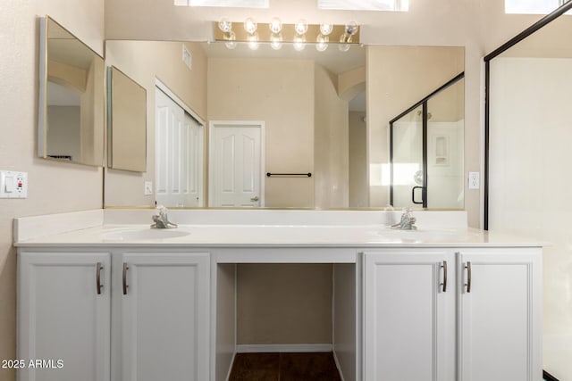 full bath featuring double vanity, a shower stall, and a sink