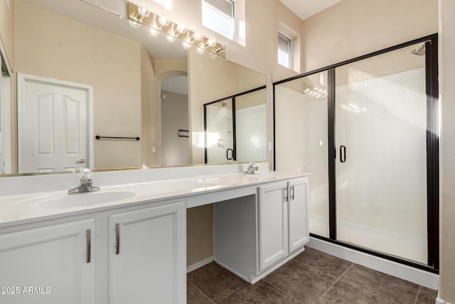 full bath featuring double vanity, a stall shower, tile patterned floors, and a sink