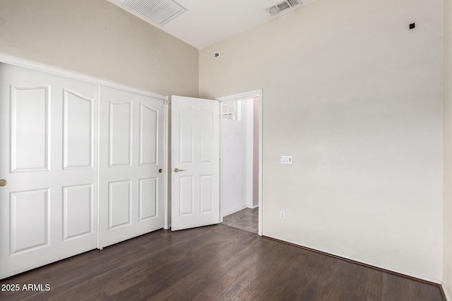 unfurnished bedroom featuring visible vents, a closet, and dark wood-style flooring