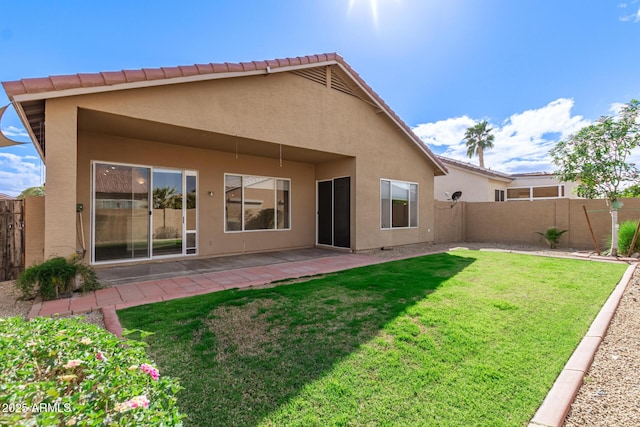 rear view of property with fence, a tile roof, stucco siding, a yard, and a patio