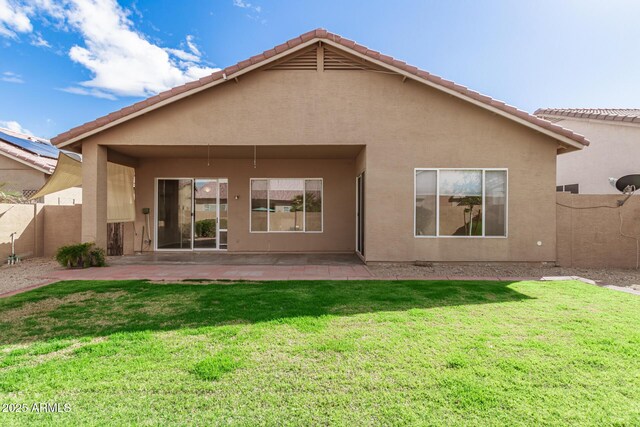 back of property featuring stucco siding, a lawn, a patio, and fence