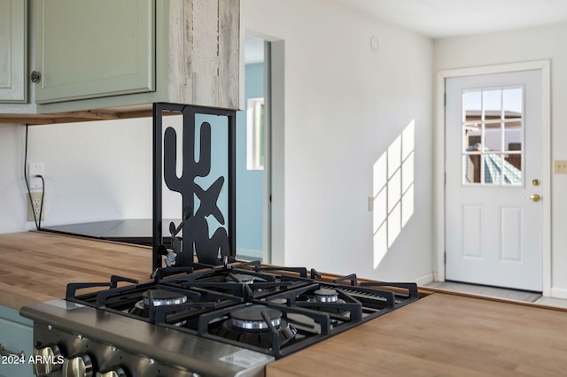 kitchen with green cabinets, black stove, and hardwood / wood-style flooring