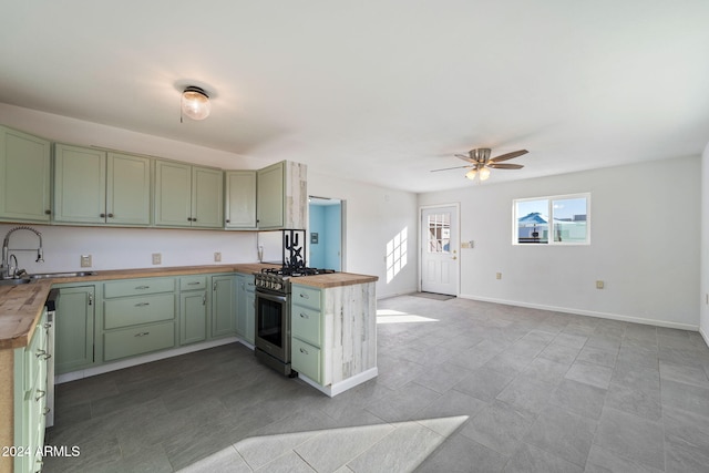 kitchen featuring ceiling fan, sink, wood counters, green cabinets, and stainless steel range with gas cooktop