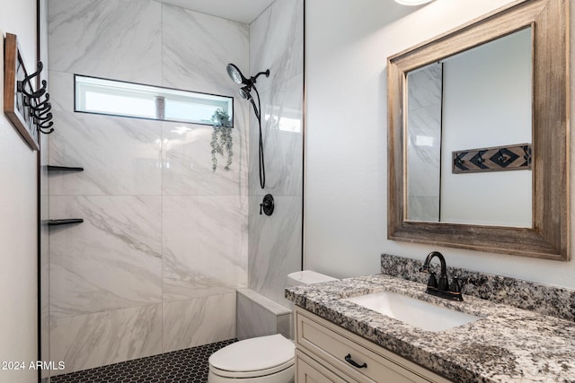 bathroom featuring a tile shower, vanity, and toilet