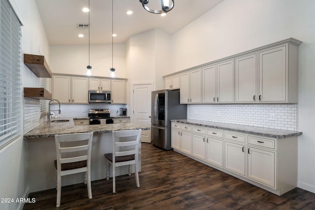 kitchen with pendant lighting, dark hardwood / wood-style flooring, kitchen peninsula, and appliances with stainless steel finishes