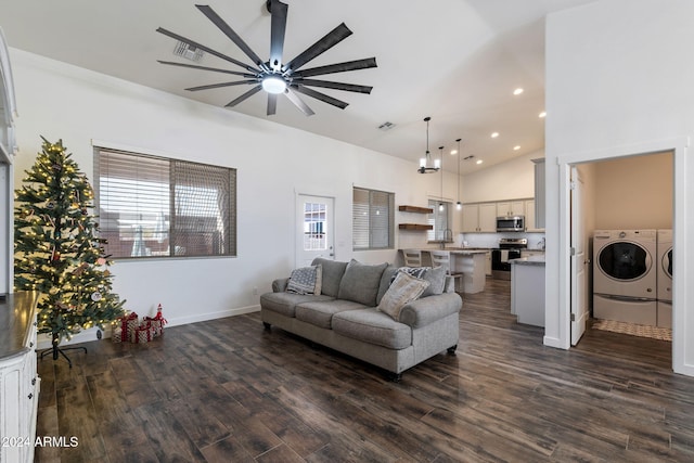 living room with a towering ceiling, ceiling fan, dark wood-type flooring, sink, and washing machine and dryer