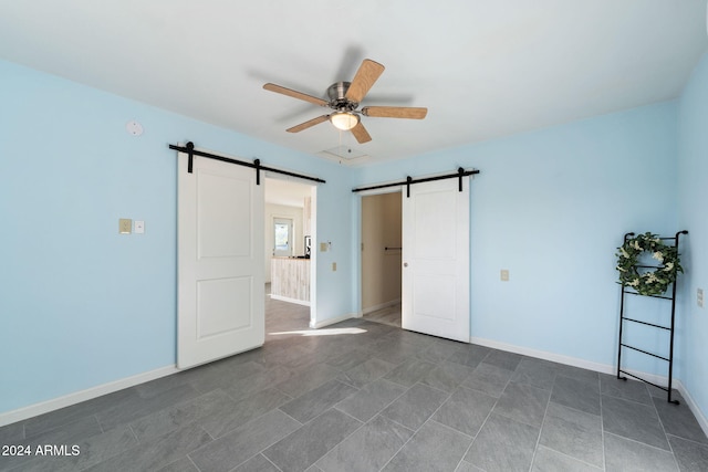 unfurnished room with a barn door and ceiling fan