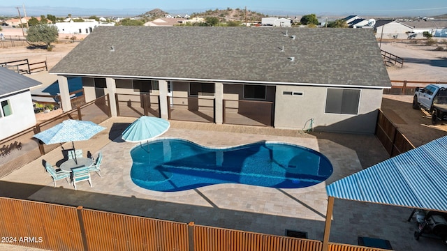 back of property featuring a patio and a fenced in pool