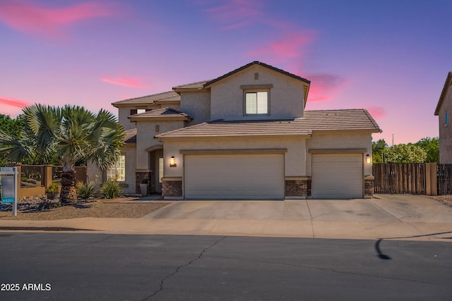 view of front facade featuring stone siding, fence, concrete driveway, stucco siding, and a garage
