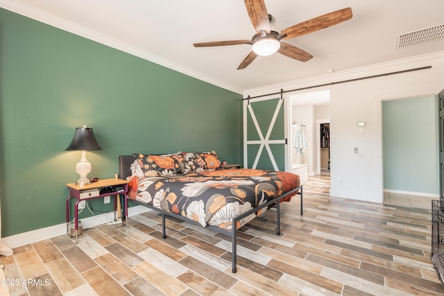 bedroom with a barn door, ornamental molding, baseboards, wood finished floors, and ceiling fan