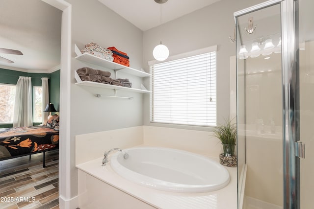 ensuite bathroom featuring healthy amount of natural light, a garden tub, a shower stall, and ceiling fan